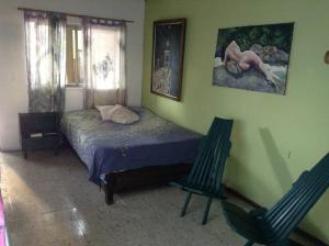 ein Schlafzimmer mit einem Bett und zwei Stühlen darin in der Unterkunft Apartamento-Galería de arte Cielo y Tierra in Medellín