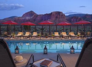 a pool with chairs and umbrellas with a view of the mountains at Capitol Reef Resort in Torrey