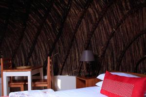 1 dormitorio con 1 cama en una cabaña de paja en Olive Country Lodge - Eswatini, en Ngwempisi
