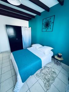 a bedroom with a large bed with blue walls at Villa Longani Passion pour des vacances bucoliques en famille in Petite Île