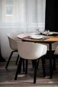 a table with two white chairs and a wooden table with wine glasses at Luxury Apartments CITY in Uzhhorod