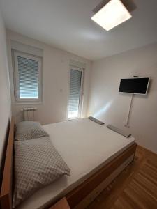 een slaapkamer met een bed en een lamp en twee ramen bij No1Apartments in Požarevac