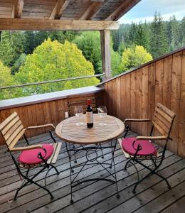 una mesa con 2 sillas y una botella de vino en una terraza en Pension Kricklsäge en Philippsreut