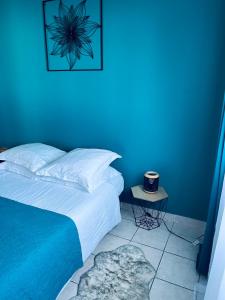 a blue bedroom with a bed and a night stand at Villa Longani Passion pour des vacances bucoliques en famille in Petite Île