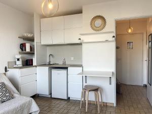 een kleine keuken met witte kasten en een tafel en kruk bij Studio le couchant in La Grande-Motte