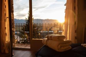 a stack of towels sitting on a bed in front of a window at Vistas espectaculares en el centro de Puigcerdà in Puigcerdà