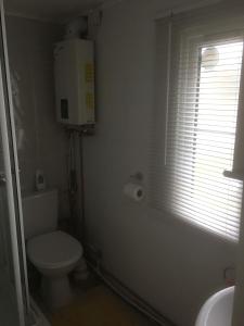 baño blanco con aseo y ventana en Tamaras Place en Leysdown-on-Sea