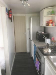 uma pequena cozinha com um fogão e um lavatório em Tamaras Place em Leysdown-on-Sea