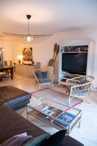 ein Wohnzimmer mit einem Sofa und einem TV in der Unterkunft Appartement Arcachon en 1ère ligne face à la mer in Arcachon