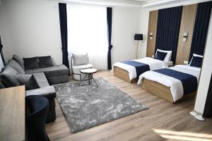 een hotelkamer met 2 bedden en een bank bij La Ruota Hotel Sharr in Dragash