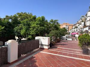 Una pasarela de ladrillos con una valla, árboles y edificios. en Casa Libertad Estepona, en Estepona