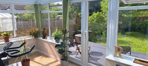 a screened in porch with windows and a table and chairs at Cosy double room in Torquay