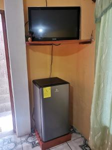 nevera pequeña con TV en la pared en Mark’s home, en Puerto Ayora