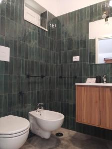 a green tiled bathroom with a toilet and a sink at Domus Al.Me in Castelmezzano
