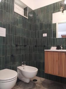 a green tiled bathroom with a toilet and a sink at Domus Al.Me in Castelmezzano +21 photos