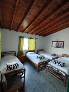 three beds in a room with wooden ceilings at Hotel Casa Verde Guatapé in Guatapé