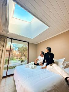 Dos personas sentadas en una cama en una habitación con ventana en Hotel El Tesoro de Elqui, en Pisco Elqui