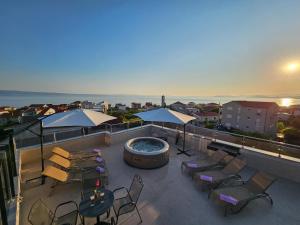 eine Dachterrasse mit einem Whirlpool sowie Tischen und Stühlen in der Unterkunft Modern villa with jacuzzi, beautiful sea view, near Split! Villa 36A in Podstrana