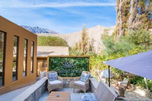 a patio with chairs and a table with mountains in the background at Hotel El Tesoro de Elqui in Pisco Elqui