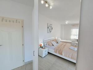 ein weißes Schlafzimmer mit einem Bett und einem Fenster in der Unterkunft Modern villa with jacuzzi, beautiful sea view, near Split! Villa 36A in Podstrana