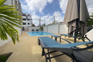 a swimming pool with an umbrella and two chairs and a table and an umbrella at SeaSand-Entire Luxury 3 BD condo - Close to beach in Flic-en-Flac