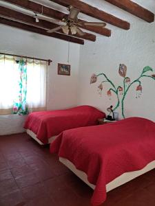 Quinta Lachaud في Chiconcuac: غرفة نوم بسريرين مع شراشف حمراء ومروحة