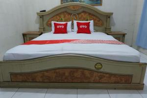 een groot bed met twee rode kussens erop bij OYO 93159 Homestay Sehat in Gresik