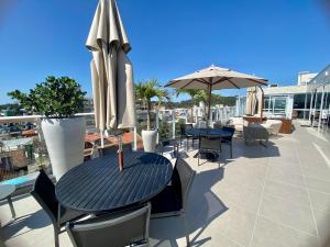 a patio with a table and chairs and an umbrella at Vila do Centro Bombinhas in Bombinhas