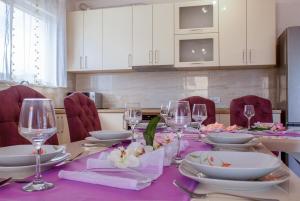 einen Esstisch mit einem lila Tischtuch und Weingläsern in der Unterkunft Modern villa with jacuzzi, beautiful sea view, near Split! Villa 36A in Podstrana
