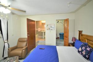 Un dormitorio con una cama azul y blanca y una silla en Cozy Locale Pearl en Port Antonio