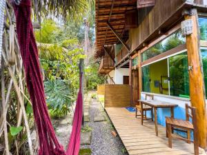 un porche de madera de una casa con mesa y sillas en Barra Quintal Studio 3, en Barra Grande