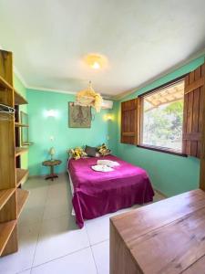 - une chambre avec un lit violet et une fenêtre dans l'établissement Barra Quintal Studio 3, à Barra Grande