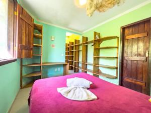 1 dormitorio con cama rosa y estanterías de madera en Barra Quintal Studio 3, en Barra Grande