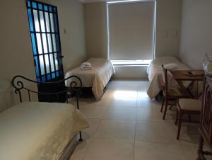 een kamer met 2 bedden, een tafel en een raam bij La rue de Rox in Corrientes