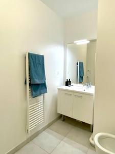 een witte badkamer met een wastafel en een spiegel bij Neuf, vue panoramique, calme, spacieux, propre in Asnières-sur-Seine
