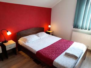 1 dormitorio con 1 cama con pared roja en Sobe i apartmani Kety, en Kragujevac