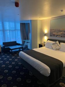 una habitación de hotel con una cama grande y una silla en Shores Holiday Apartments, en Blackpool