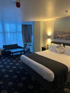 a hotel room with a large bed and a chair at Shores Holiday Apartments in Blackpool