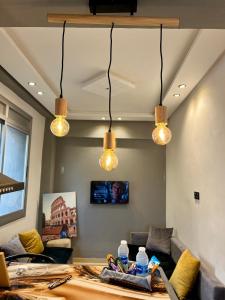 uma sala de estar com três luzes penduradas no tecto em Private apartment, bright and quiet em Tânger