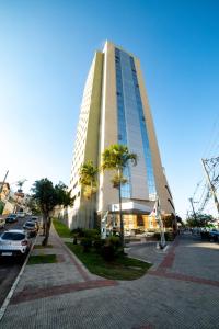 een hoog gebouw met auto's geparkeerd voor het bij Nobile Inn Pampulha in Belo Horizonte