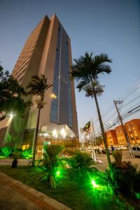 un edificio alto con palmeras delante en Nobile Inn Pampulha en Belo Horizonte