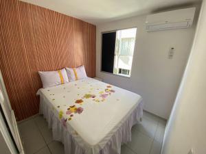 ein kleines Schlafzimmer mit einem Bett mit Blumen darauf in der Unterkunft Apartamento na Grande Natal (Condomínio Barcas) in Natal