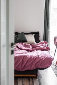 a bed with pink sheets and pillows in a room at Artistic Urban Retreat Olomouc in Olomouc