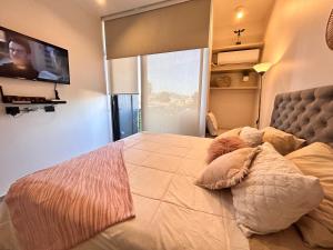 a bedroom with a large bed with a tv on the wall at LOFT 31 Villa Alemana BEEHOUSE in Villa Alemana