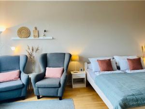 ein Schlafzimmer mit zwei blauen Stühlen und einem Bett in der Unterkunft Ferienwohnung Meernähe in Fehmarn