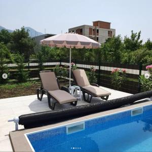 two chairs and an umbrella next to a swimming pool at lux apartmani Porte Nouva in Sutomore +9 photos
