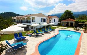 a pool with chairs and umbrellas and a house at Antigone Thassos Hotel in Limenas