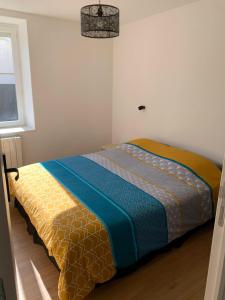 Le Chazottier في Brindas: غرفة نوم مع سرير مع لحاف ملون