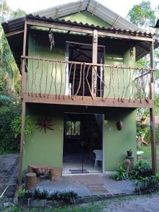 una pequeña casa verde con terraza de madera en Chalé Encantadas Eco Ilha Preserve en Ilha do Mel