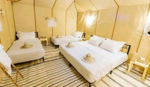 a room with two beds in a tent at Maria Sahara Camp in Merzouga